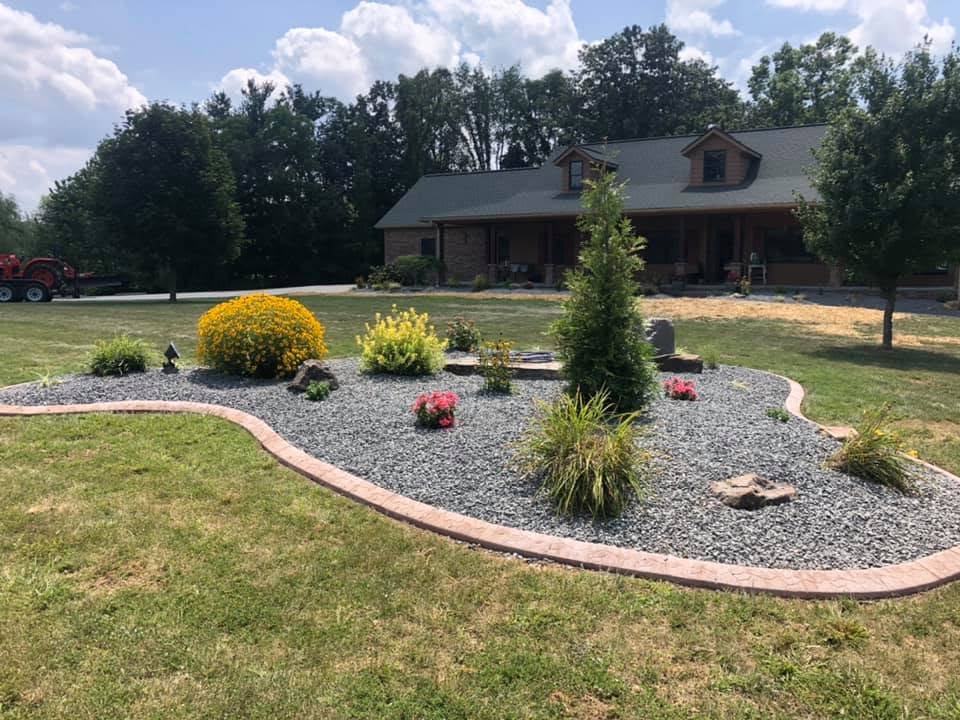 Large curved island bed with flowering shrubs and decorative stone