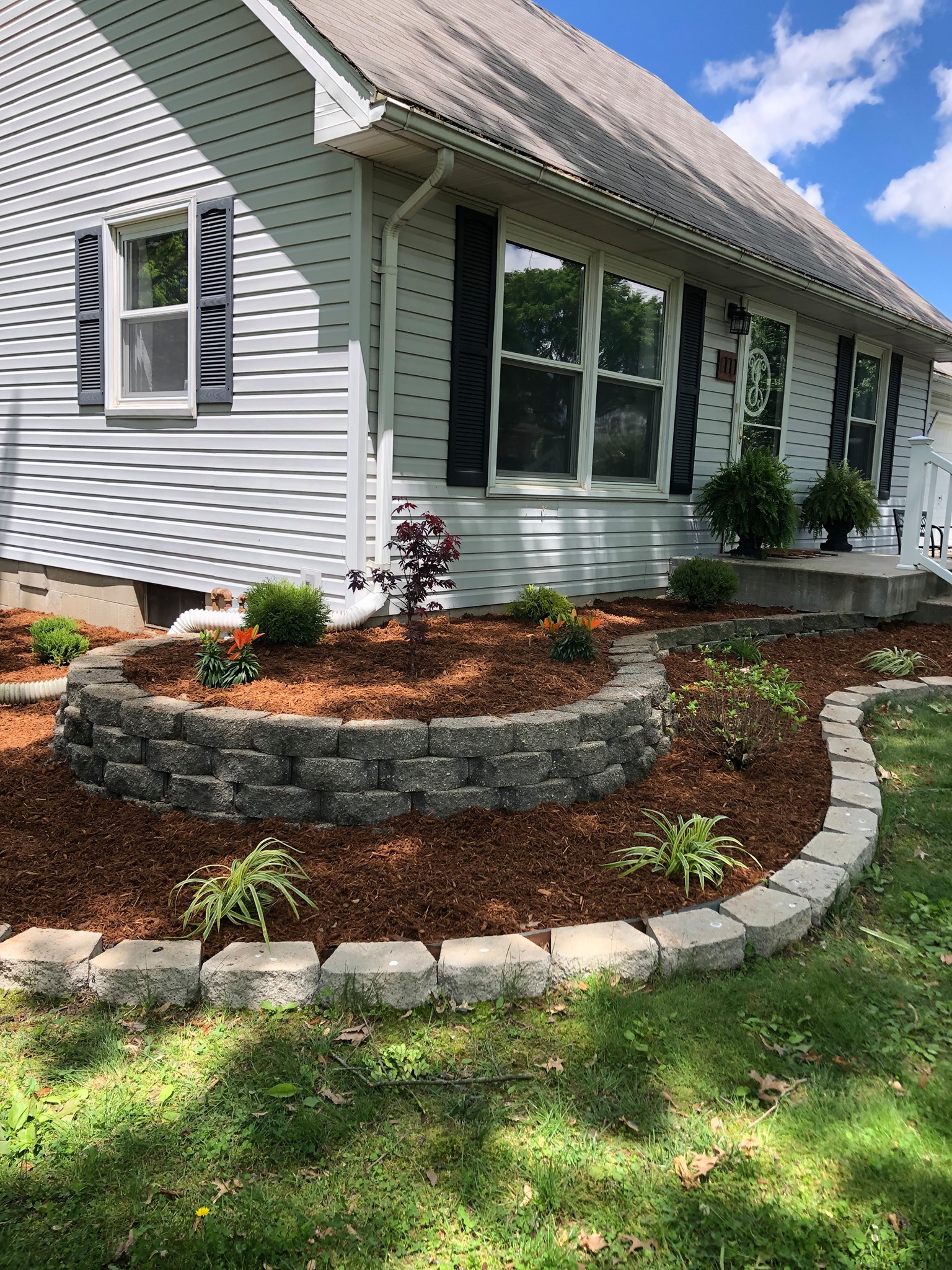 Installed landscape bed with layered shrubs and stone border
