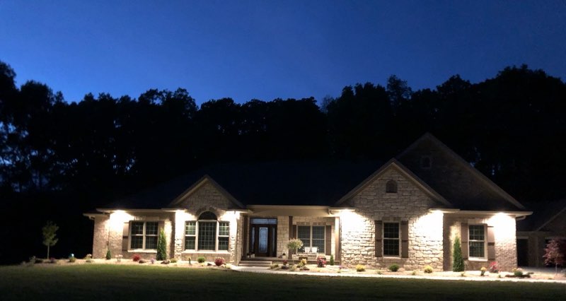 Ranch home with landscape lighting and foundation plantings at night