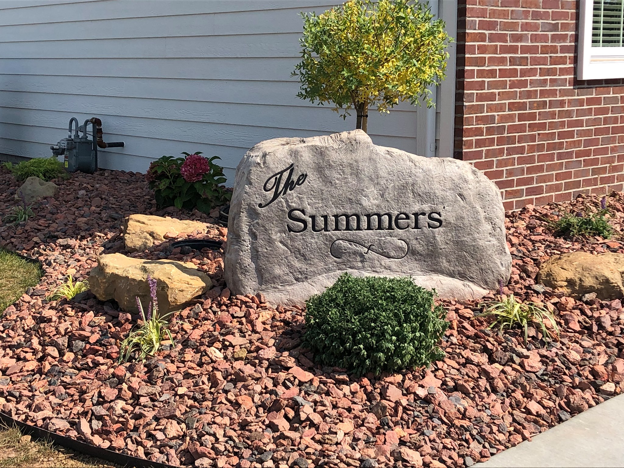 Custom engraved boulder set in a river rock bed