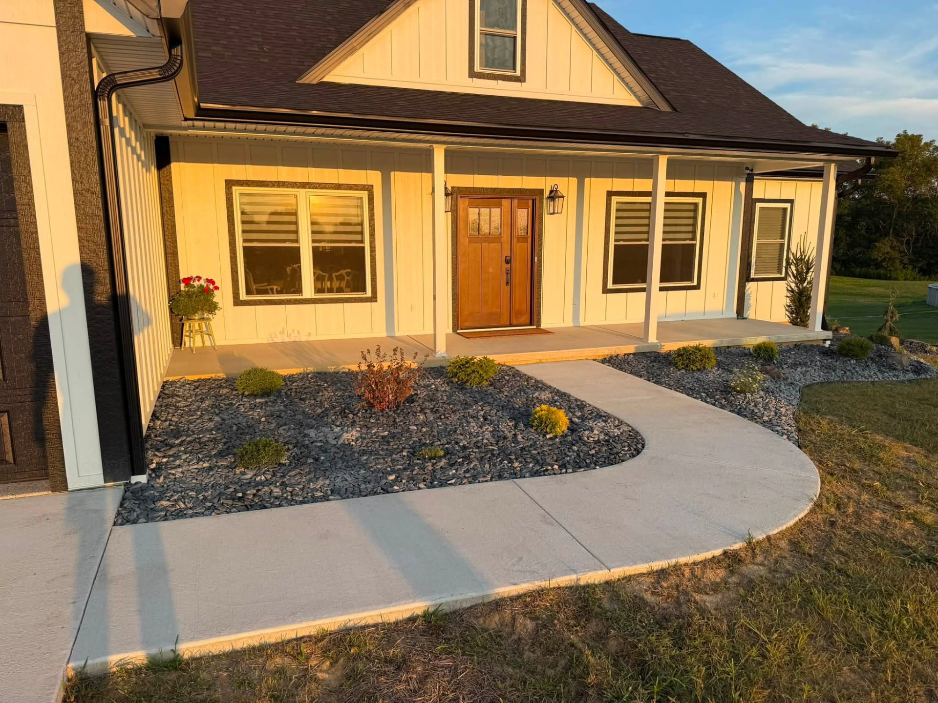 Modern white home with sweeping concrete walkway and finished decorative rock beds